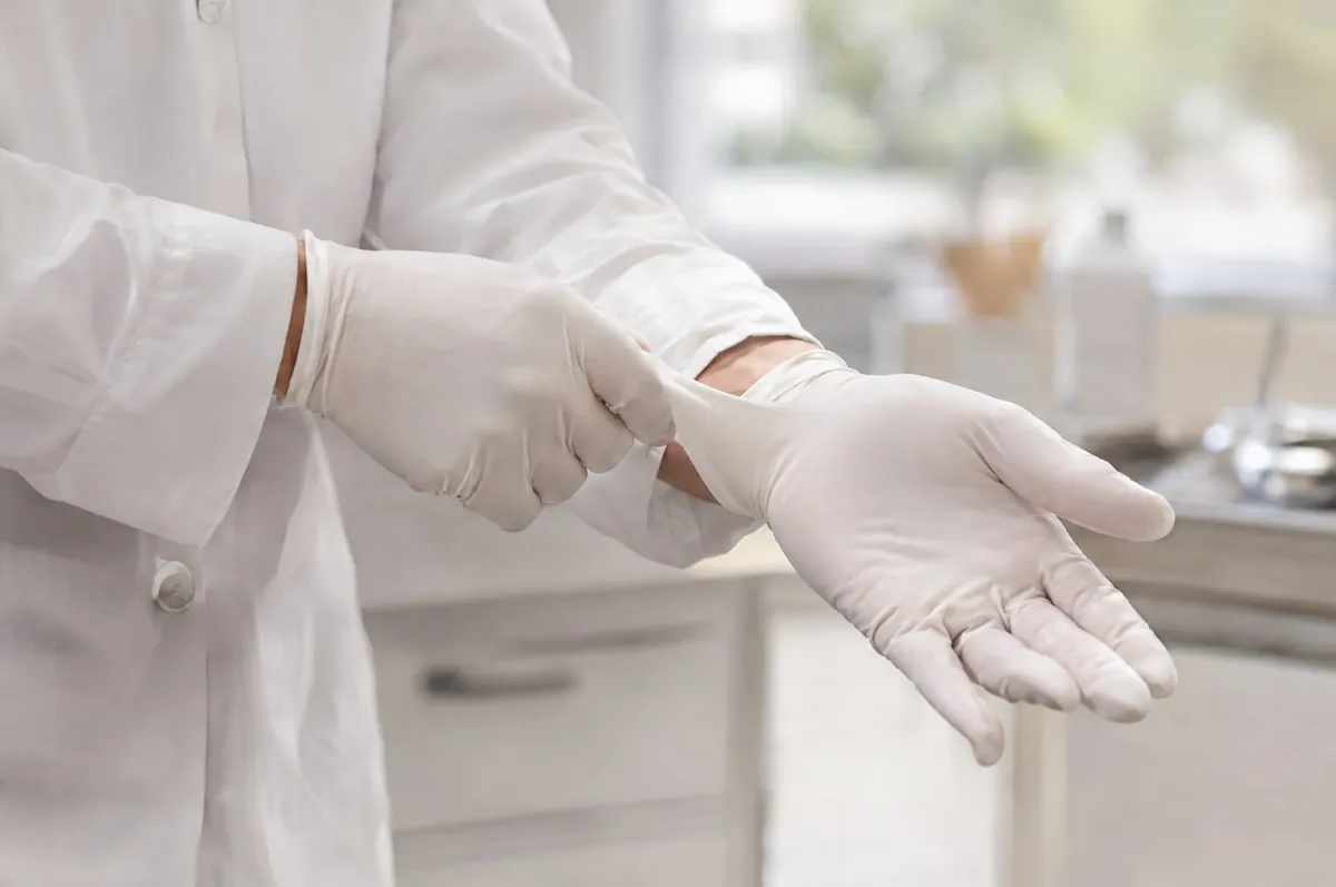 Symbolbild: Hände ziehen sterile Handschuhe an